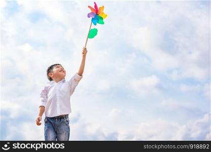 Boy holding colorful pinwheel in windy at outdoors. Children portrait and kids playing theme.