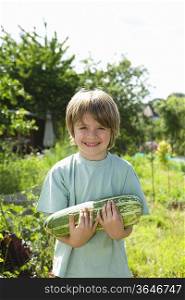 Boy holding marrow in garden, portrait