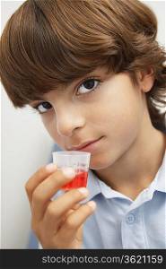 Boy holding medicine in liquid measure,portrait