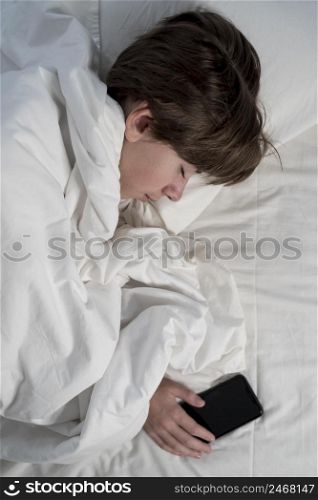 boy holding phone while sleeping