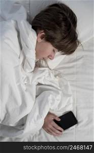 boy holding phone while sleeping