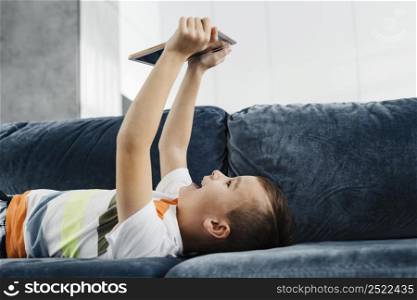 boy home laying couch using digital tablet