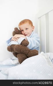 Boy hugging teddy bear in bed