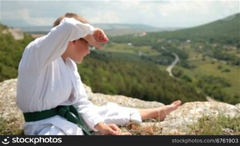 boy in a kimono sits resting on the edge of the cliff
