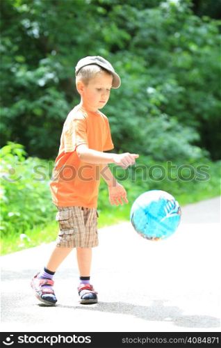 Boy in action young kid playing with ball in park outdoors. Healthy leisure time