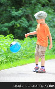 Boy in action young kid playing with ball in park outdoors. Healthy leisure time