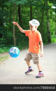 Boy in action young kid playing with ball in park outdoors. Healthy leisure time