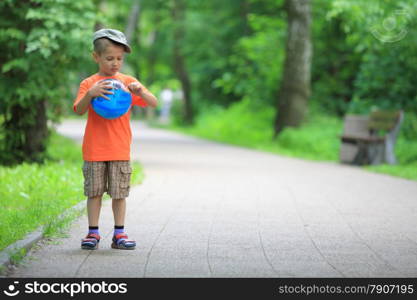 Boy in action young kid playing with ball in park outdoors. Healthy leisure time