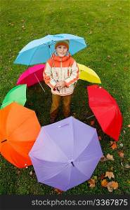 Boy in autumn park, in environment of multi-coloured umbrellas. Top view.