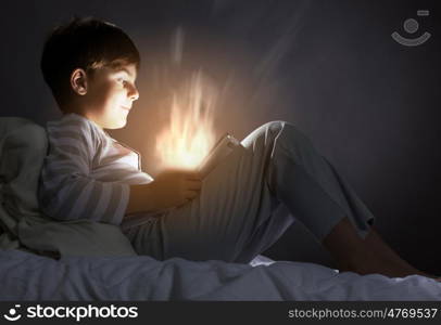 Boy in bed. Cute boy sitting in bed and using tablet pc