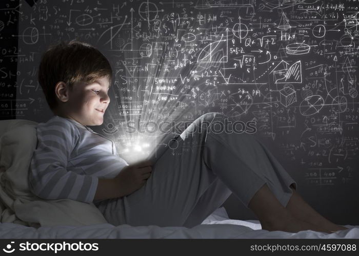 Boy in bed. Cute little boy sitting in bed and using tablet pc