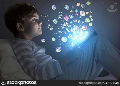 Boy in bed. Cute little boy sitting in bed and using tablet pc