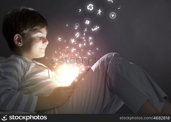 Boy in bed. Cute little boy sitting in bed and using tablet pc