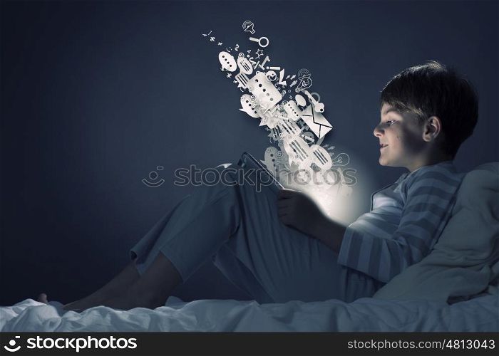 Boy in bed. Cute little boy sitting in bed and using tablet pc