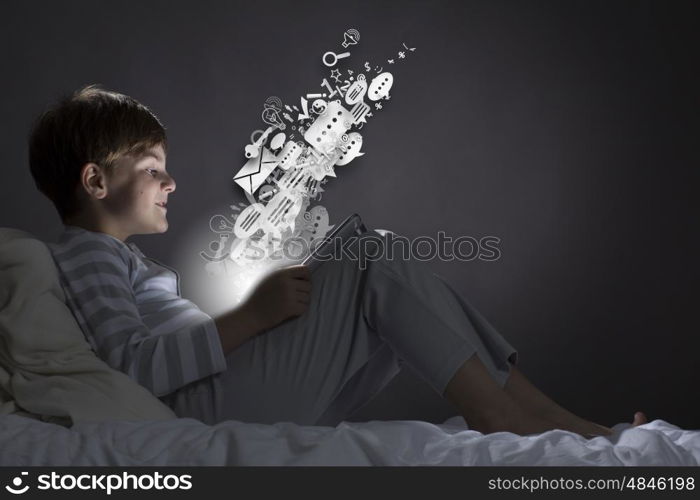 Boy in bed. Cute little boy sitting in bed and using tablet pc