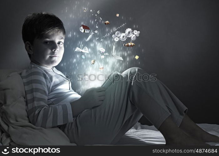 Boy in bed. Cute little boy sitting in bed and using tablet pc