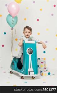 Boy in costume designer on a toy bike with balloons on a white background. boy on a toy motorcycle on a white background