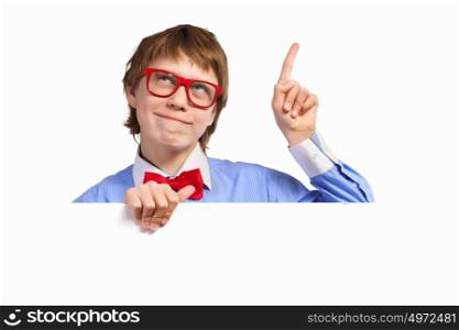Boy in red glasses holding white square. Image of young boy smiling thoughtfully holding white square. Place for advertisement