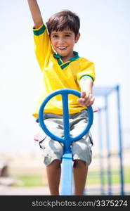 Boy in soccer uniform playing in the park and taking ride on swing