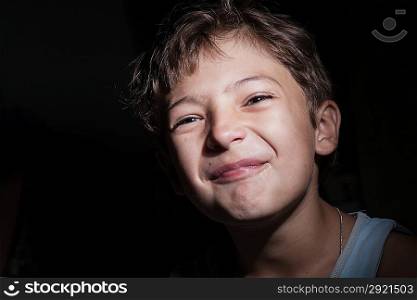 boy in the dark cry or make faces, focused light on the face, background in the dark