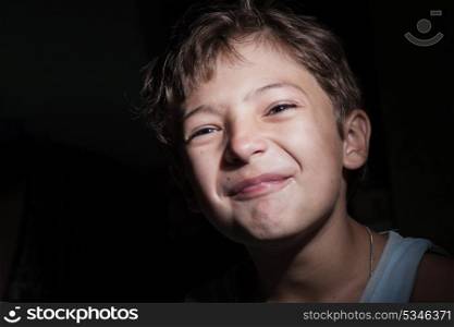 boy in the dark cry or make faces, focused light on the face, background in the dark