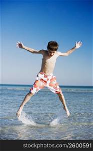 Boy jumping in water with his arms outstretched