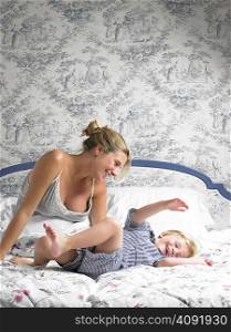 Boy jumping on his mother&acute;s bed
