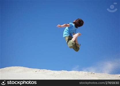 boy jumps on sand