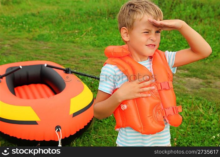 boy keeps watch and inflatable boat on lawn