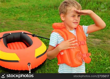 boy keeps watch and inflatable boat on lawn