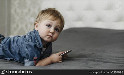 boy laying bed holding mobile phone
