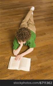 Boy laying on the floor reading a book