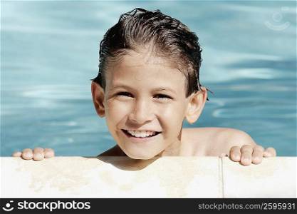 Boy leaning at the poolside and smiling