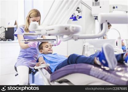 boy leaning dental chair getting treatment by female dentist