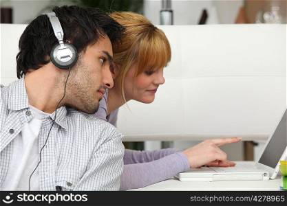 Boy listening to music and girl using laptop computer