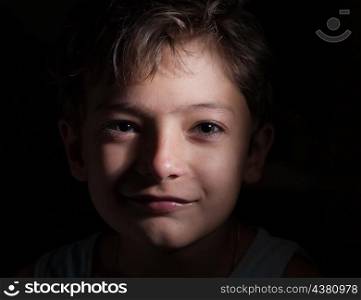 boy look at camera in the dark, focused light on the face only