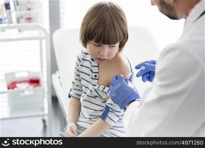 Boy looking at doctor injecting syringe in hospital