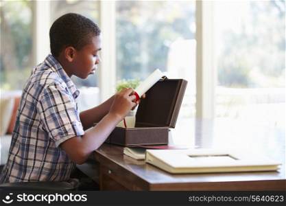 Boy Looking At Document In Keepsake Box On Desk