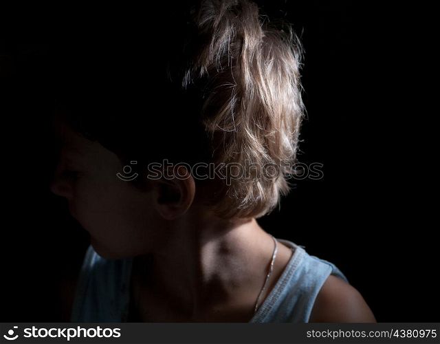boy looking away in the dark, focused light on the one side