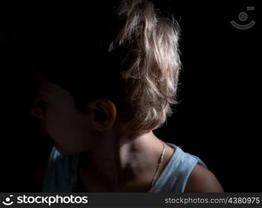 boy looking away in the dark, focused light on the one side