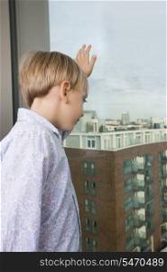 Boy looking out through window at home