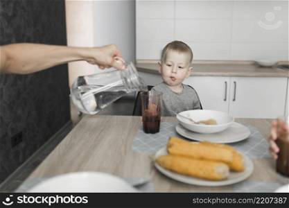 boy looking person pouring water glass breakfast
