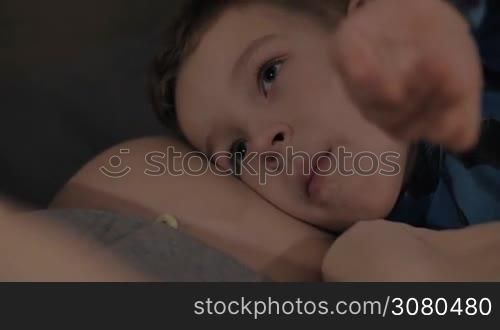 Boy lying on the belly of pregnant mother. He wants to listen his baby brother or sister kicking