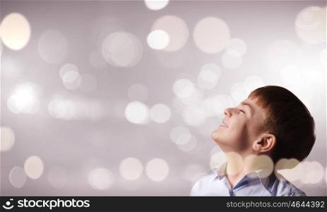 Boy making a wish. Cute boy with closed eyes against bokeh background