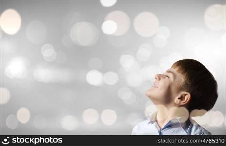 Boy making a wish. Cute boy with closed eyes against bokeh background