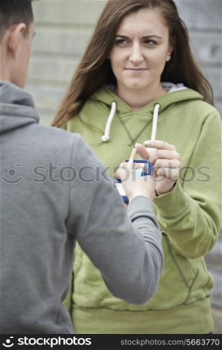 Boy Offering Teenage Girl Cigarette Outdoors