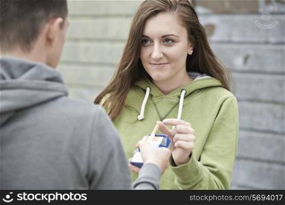 Boy Offering Teenage Girl Cigarette Outdoors