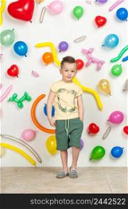 boy on a white background with colorful balloons. boy in a tank top and shorts on a white background with balloons in the shape of a heart. boy in the background of balls