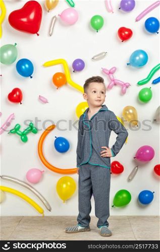 boy on a white background with colorful balloons. boy in pajamas on a white background with balloons in the shape of heart. boy in the background of balls