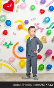 boy on a white background with colorful balloons. boy in pajamas on a white background with balloons in the shape of heart. boy in the background of balls